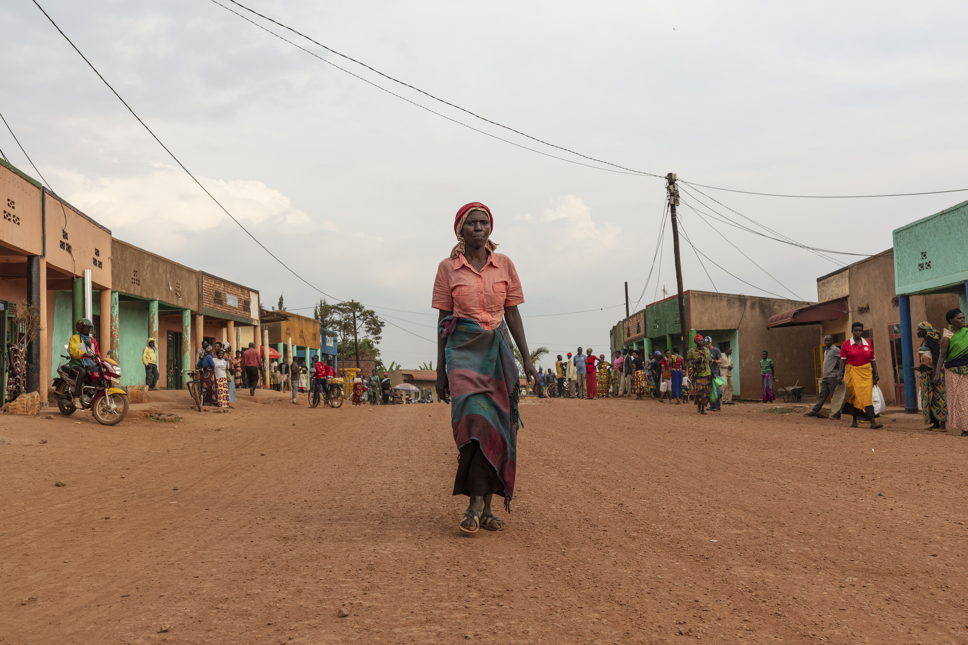 A woman stands tall in the middle of a road in Rwanda, centered in the frame; Photo Credit: GiveWith